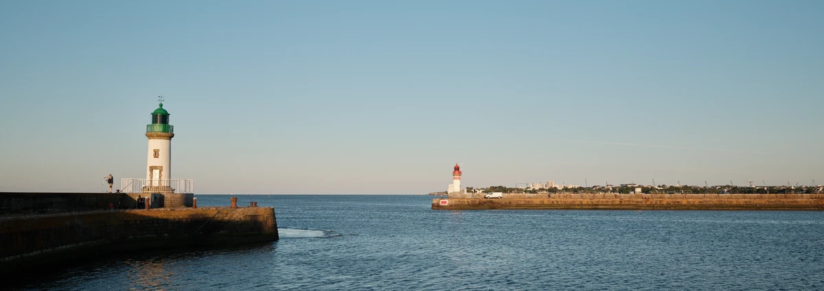 Le phare de la jetée Est (vert) et le phare de la jetée Ouest (rouge) encadrant l'entrée du port de Saint-Nazaire, mer calme.
